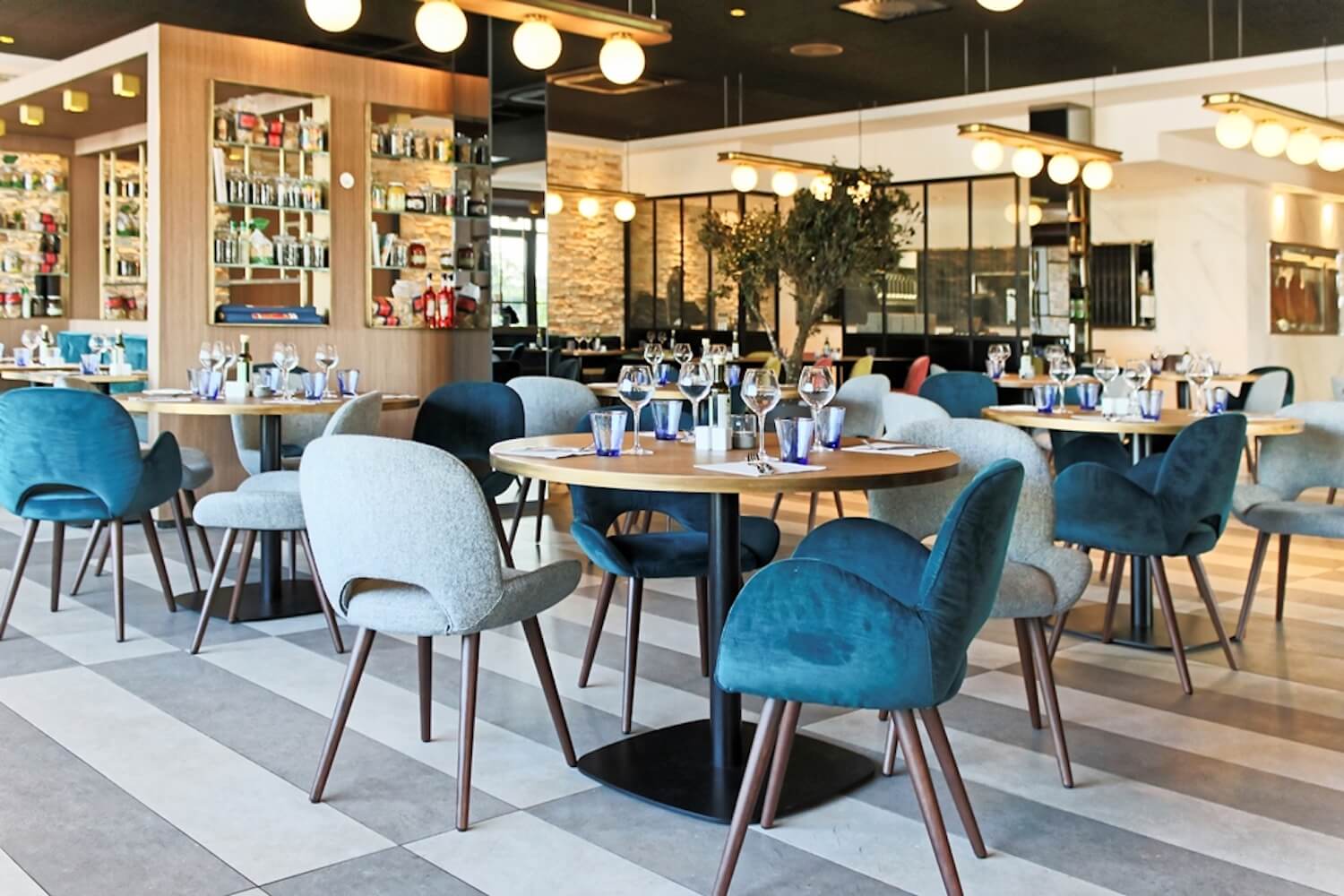 Salle d’Il Ristorante Saint-Herblain, photographie du site officiel : tables dressées et fauteuils bleus.
