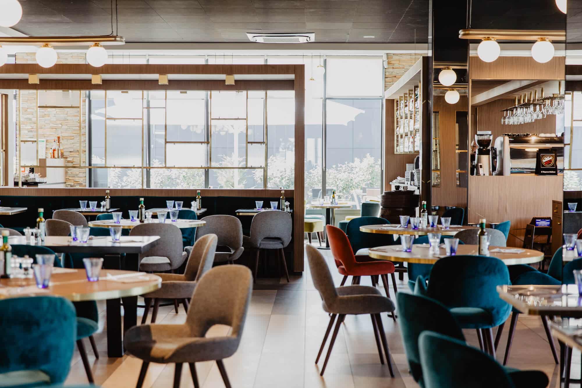 Salle du restaurant Il Ristorante fournie pour la sortie à Saint-Herblain : tables dressées et fauteuils colorés.